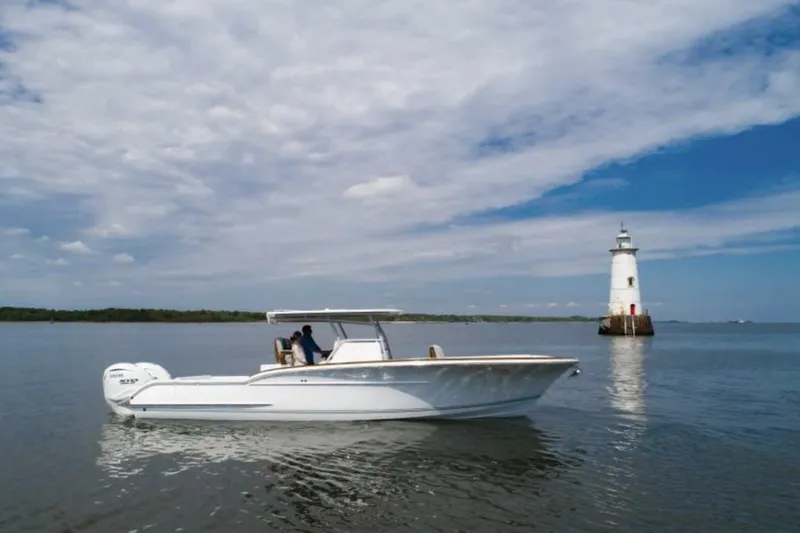 The Image of 2027 Buddy Davis 34 boat cruising near a lighthouse under a partly cloudy sky. - 1