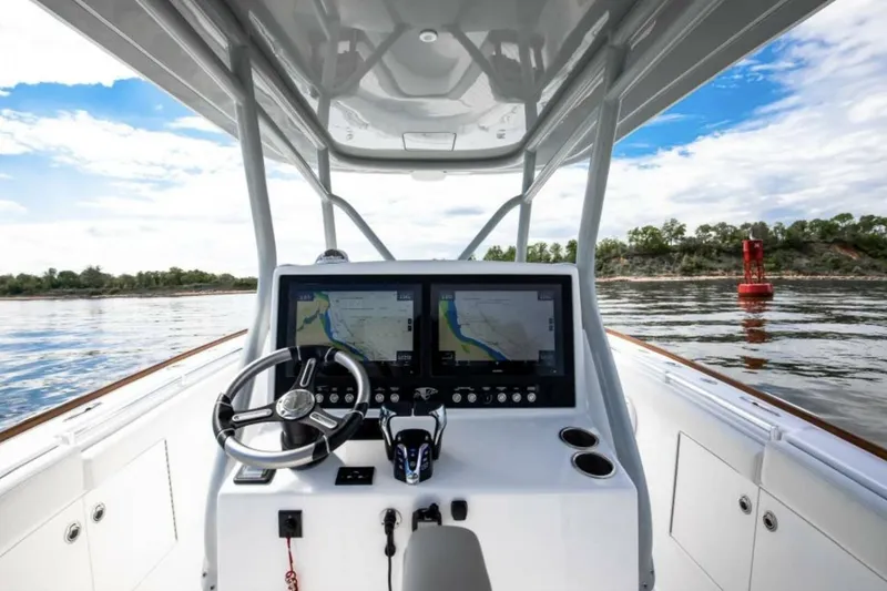 Slide: The Image of 2027 Buddy Davis 34 boat helm with dual navigation screens on calm water. - 6