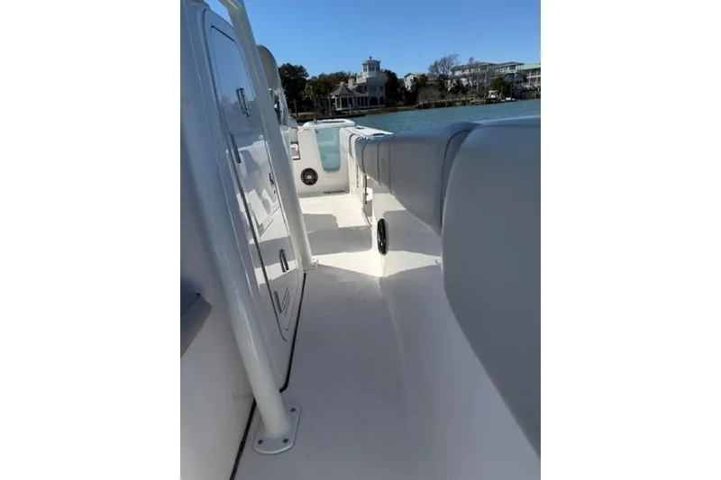 Slide: The Image of 2023 Sea Fox 248 Commander boat interior with seating and storage, docked near waterfront homes. - 34