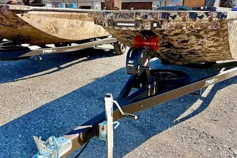 Slide: The Image of 2026 Thor Fish Hammer 1754 LR boat trailer with camouflage design on gravel surface. - 8