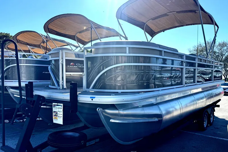 The Image of 2024 Sun Tracker SportFish 22 XP3 pontoon boat with canopy, parked on a trailer. - 0