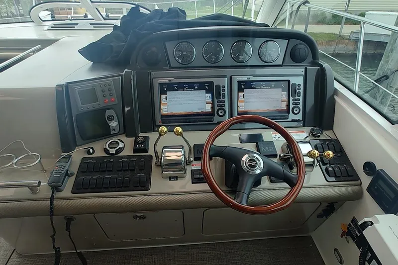 Slide: The Image of 2006 Sea Ray 48 Sundancer helm with dual screens and wooden steering wheel. - 10