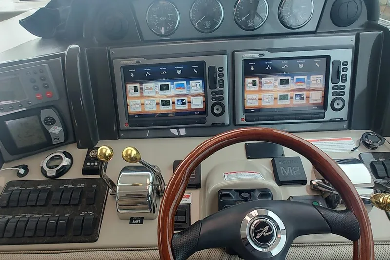 Slide: The Image of Control panel of a 2006 Sea Ray 48 Sundancer yacht with dual screens and steering wheel. - 9