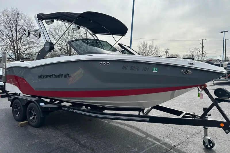 Slide: The Image of 2023 MasterCraft NXT22 boat on trailer, gray and red design, parked outdoors. - 3
