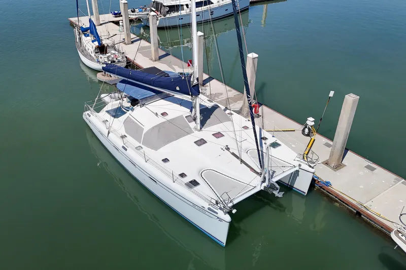 Slide: The Image of Boat lift hoisting 2001 Privilege 435 catamaran under clear blue sky. - 151