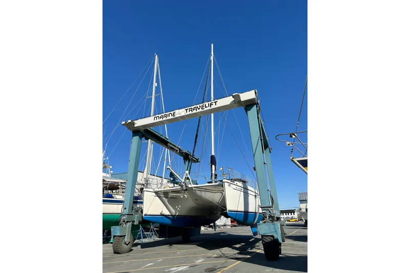 Slide: The Image of Boat lift hoisting 2001 Privilege 435 catamaran under clear blue sky. - 48