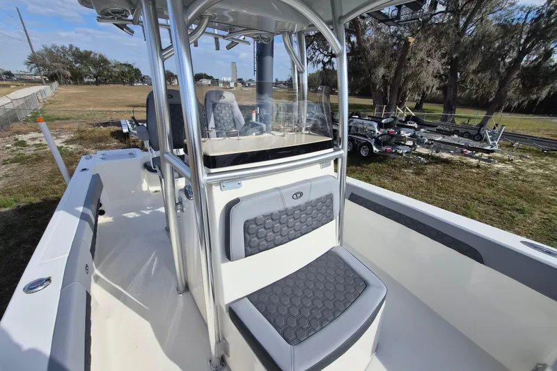 Slide: The Image of 2026 Defiance Catalina 240 boat interior with seating and console, parked outdoors. - 16