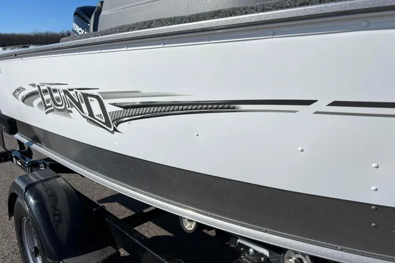 Slide: The Image of 2016 Lund 1675 Impact Sport boat on trailer, featuring bold logo and sleek design. - 16