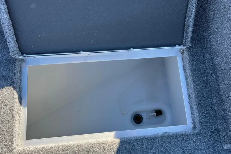 Slide: The Image of 2016 Lund 1675 Impact Sport boat storage compartment with open lid, carpeted interior. - 35