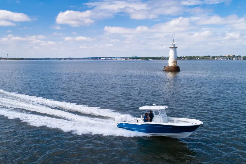 Slide: The Image of 2027 Buddy Davis 28 Center Console boat cruising near a lighthouse on a sunny day. - 10