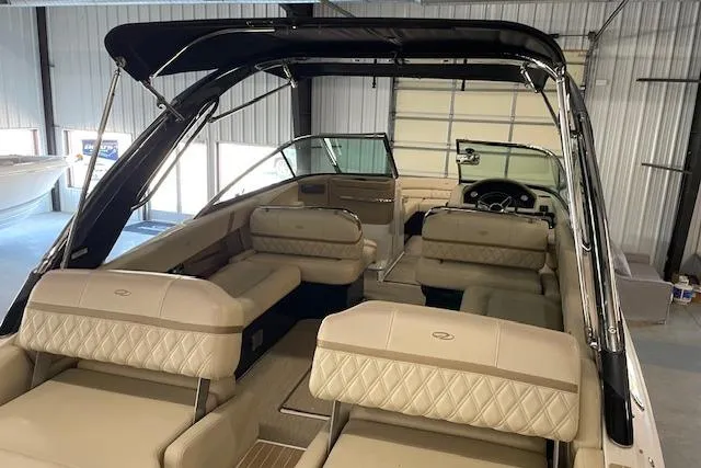 Slide: The Image of 2019 Regal 29 OBX boat interior with beige seating and black canopy in a garage. - 20
