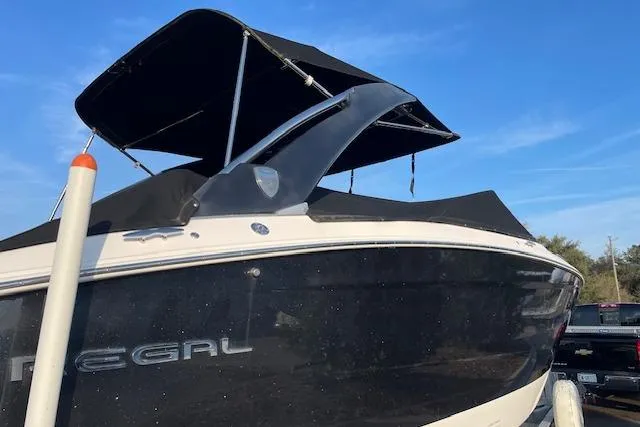 Slide: The Image of 2019 Regal 29 OBX boat with black hull and canopy under blue sky. - 3