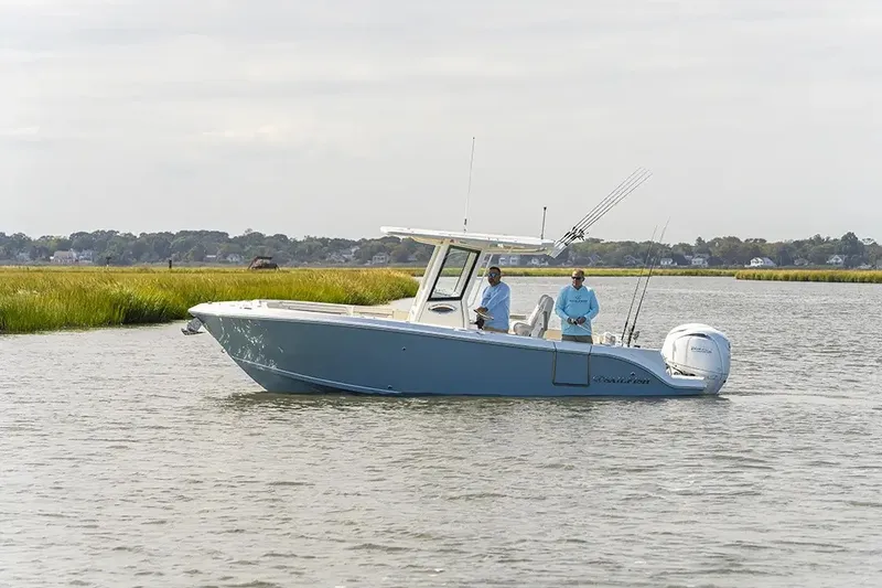 Slide: The Image of Two people stand on a blue Sailfish 252 CC boat on calm water. - 24