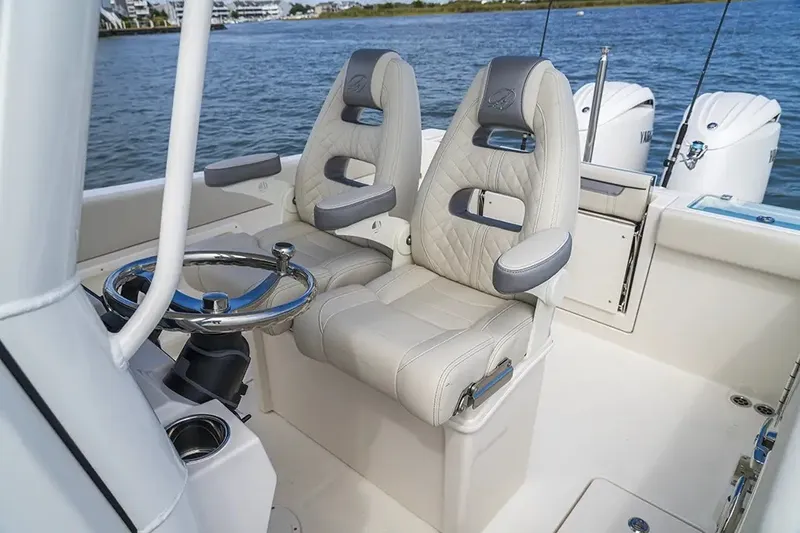 Slide: The Image of The image shows the helm of a Sailfish 252 CC boat with two cushioned seats and a steering wheel. - 27