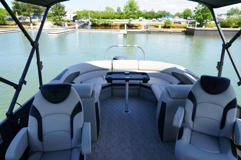 Slide: The Image of 2026 Berkshire 24 RFX LE pontoon boat interior with plush seating and table on calm water. - 15