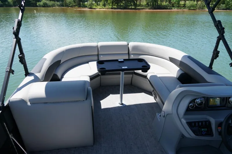 Slide: The Image of 2026 Berkshire 24 RFX LE pontoon boat interior with plush seating and table on a lake. - 16