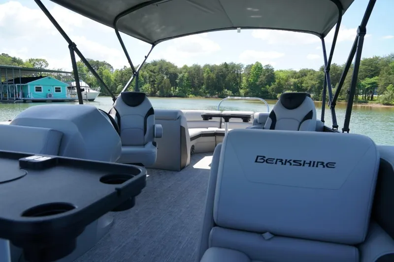 Slide: The Image of 2026 Berkshire 24 RFX LE pontoon boat interior with seating and canopy on a scenic lake. - 9