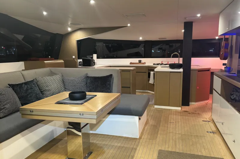 Slide: The Image of Luxurious NEEL 51 trimaran deck with cushioned seating, 2020 model, under clear blue sky. - 7