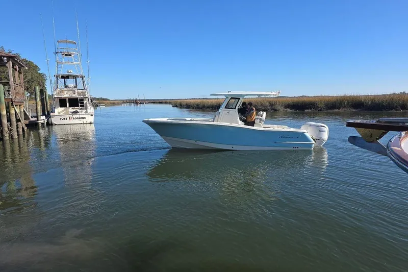 Slide: The Image of 2026 Pioneer 250 Pelagic boat navigating a calm waterway under clear blue skies. - 7