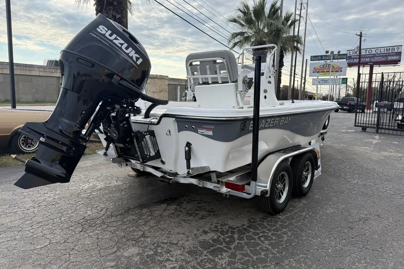 Slide: The Image of 2026 Blazer PureBay 2200 boat with Suzuki outboard motor on a trailer. - 2