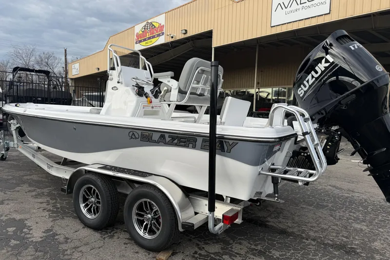 Slide: The Image of 2026 Blazer PureBay 2200 boat with Suzuki engine on trailer, parked outside dealership. - 5
