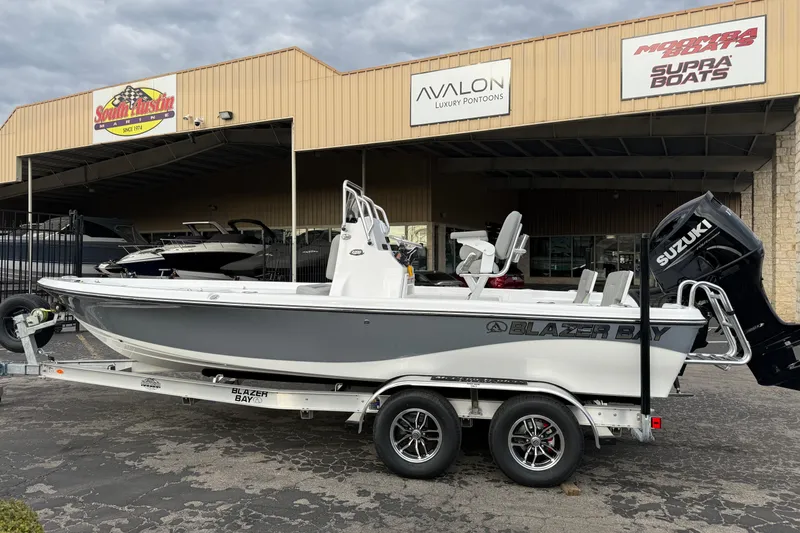 Slide: The Image of 2026 Blazer PureBay 2200 boat on trailer outside dealership, featuring Suzuki engine. - 6