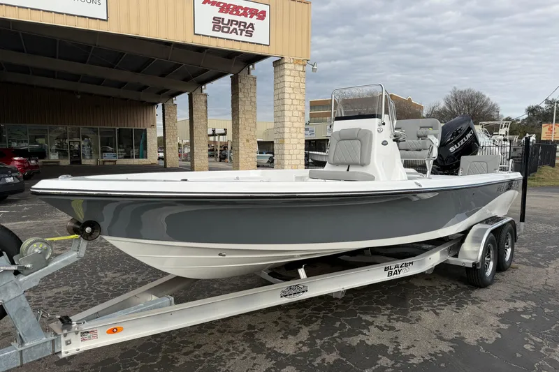 Slide: The Image of 2026 Blazer PureBay 2200 boat on trailer, parked outside dealership. - 7