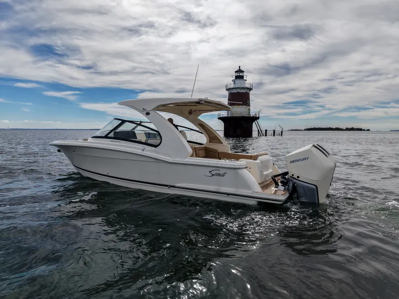 Slide: The Image of A 2027 Scout 288 Dorado boat cruising on calm waters near a lighthouse. - 3