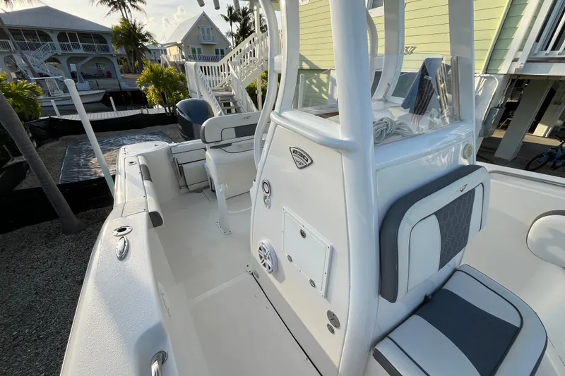 Slide: The Image of 2017 Tidewater 230 CC Adventure boat, white interior, docked near coastal homes. - 11