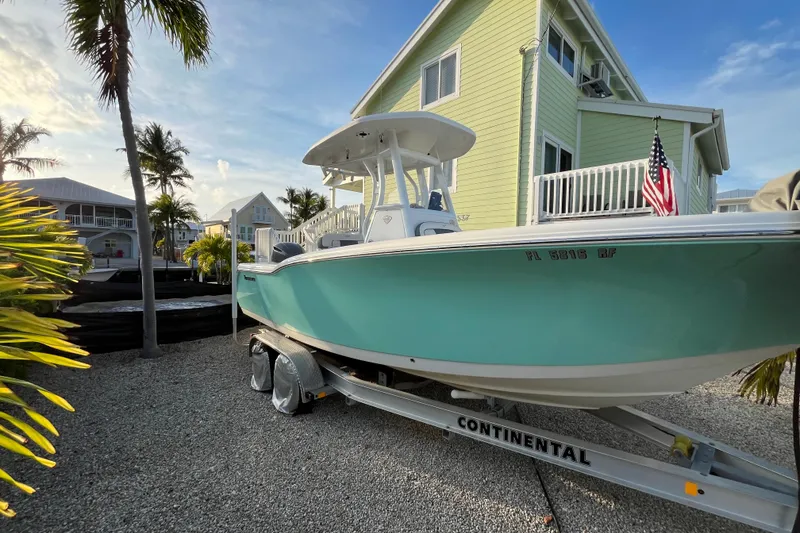 Slide: The Image of 2017 Tidewater 230 CC Adventure boat on trailer near tropical house. - 6