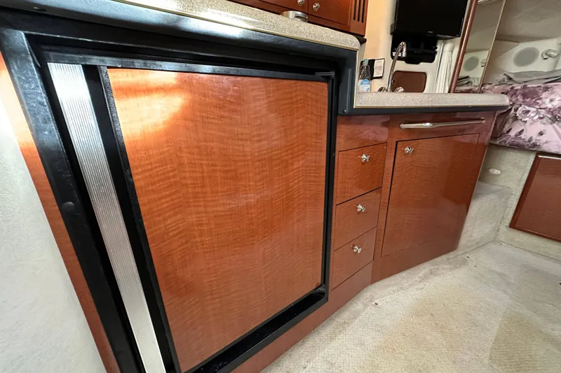 Slide: The Image of 2002 Sea Ray 340 Sundancer cabin interior with wood cabinetry and compact refrigerator. - 27