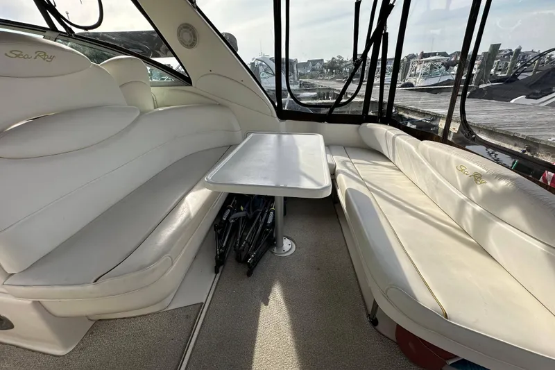Slide: The Image of 2002 Sea Ray 340 Sundancer interior with white seating and table, dockside view. - 29