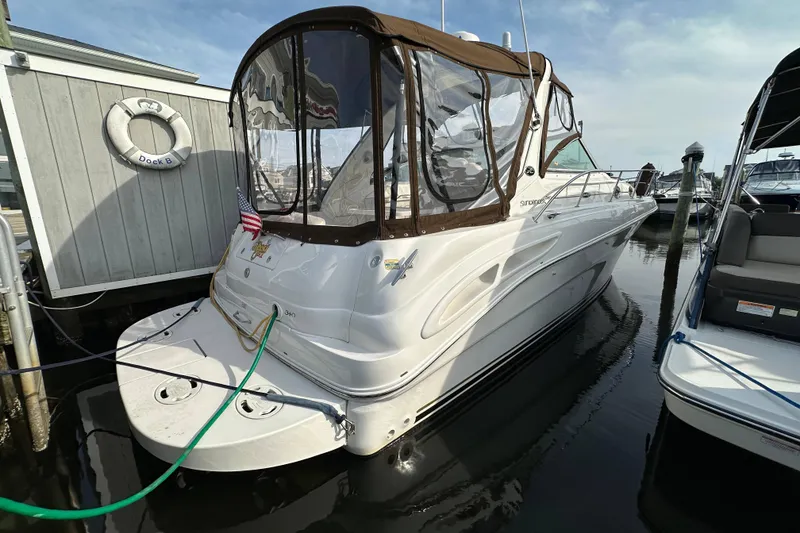 Slide: The Image of 2002 Sea Ray 340 Sundancer docked, featuring a brown canopy and American flag. - 30