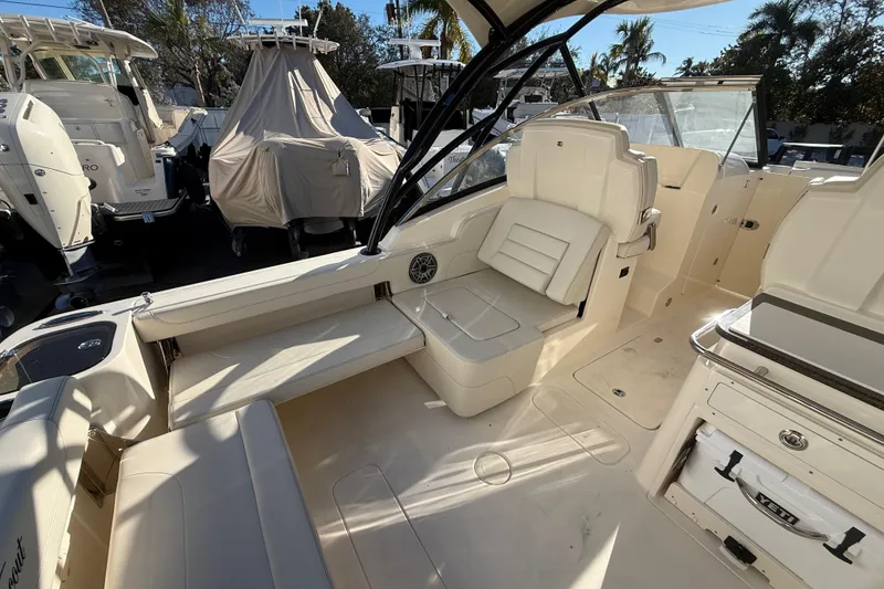 Slide: The Image of 2026 Scout 255 Dorado boat interior with seating and storage, in a sunny marina setting. - 11