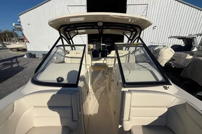 Slide: The Image of 2026 Scout 255 Dorado boat interior with seating and windshield, docked near a white building. - 21