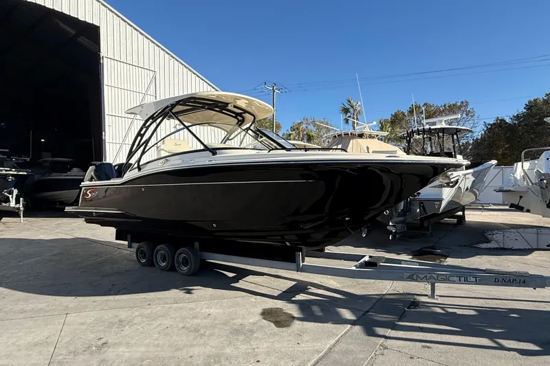 Slide: The Image of 2026 Scout 255 Dorado boat on trailer, parked outside a large warehouse. - 4