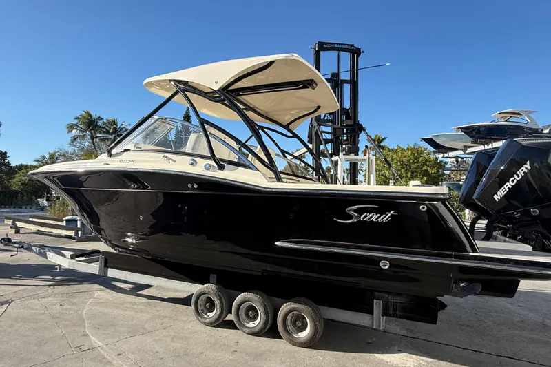 Slide: The Image of 2026 Scout 255 Dorado boat on trailer, black hull, sunny day, palm trees in background. - 6
