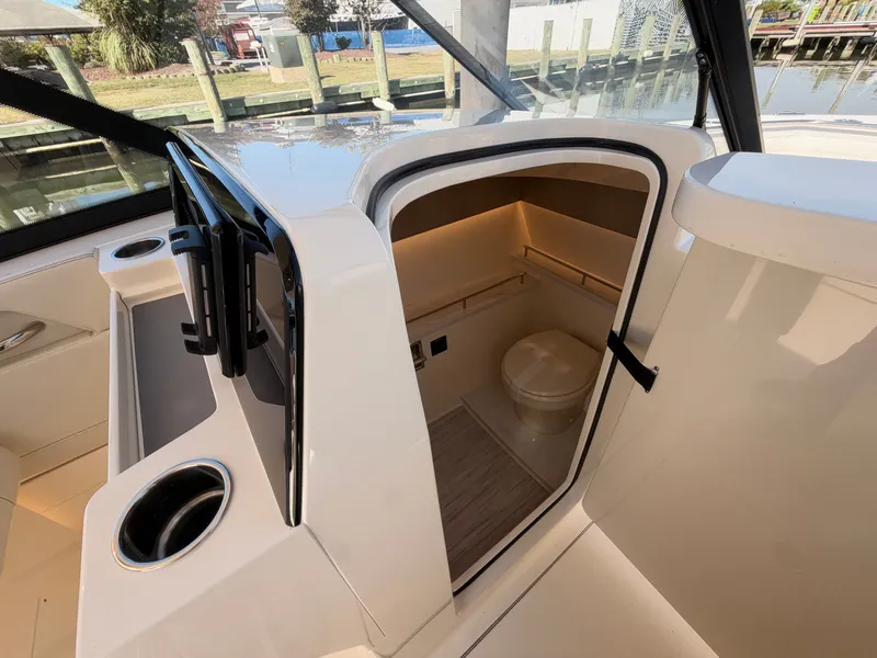 Slide: The Image of The image shows the interior of a 2027 Scout 288 Dorado boat with a small toilet. - 37