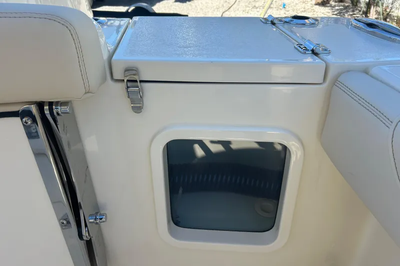 Slide: The Image of 2026 Scout 220 XSF boat storage compartment with latch and window. - 10