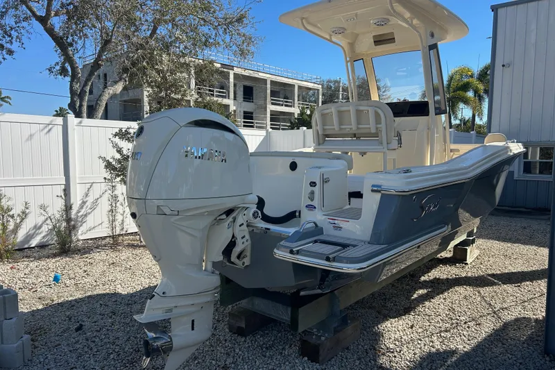 Slide: The Image of 2026 Scout 220 XSF boat with Yamaha engine, parked outdoors on gravel. - 3