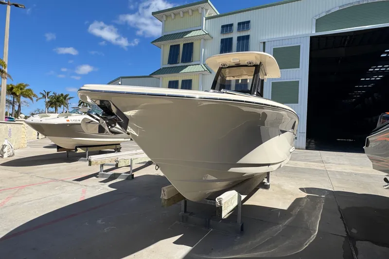 Slide: The Image of 2025 Scout 260 LXF boat displayed outdoors near a large building. - 2