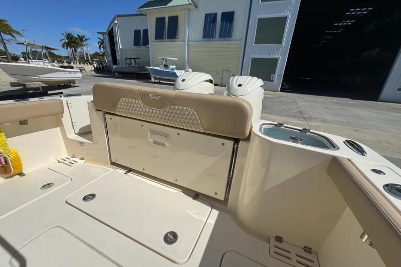 Slide: The Image of 2025 Scout 260 LXF boat interior with seating and storage, docked near a marina. - 27