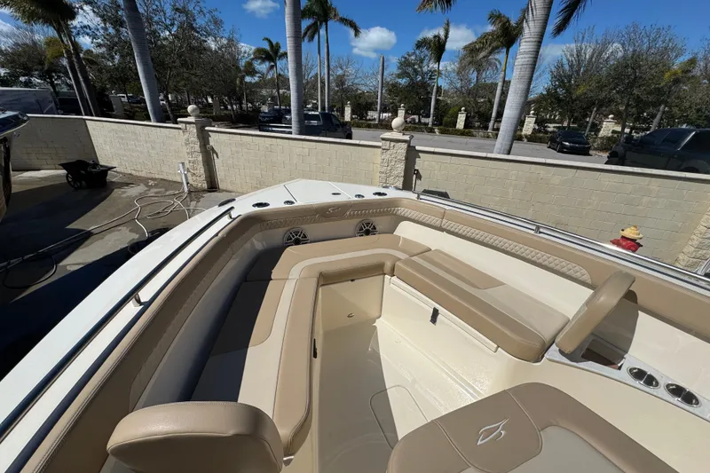 Slide: The Image of 2025 Scout 260 LXF boat interior with beige seating and palm trees in the background. - 9