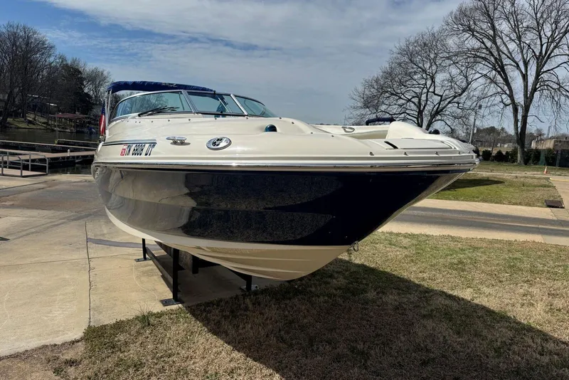 Slide: The Image of 2006 Sea Ray 240 Sundeck boat on trailer, parked near a lake under a cloudy sky. - 10