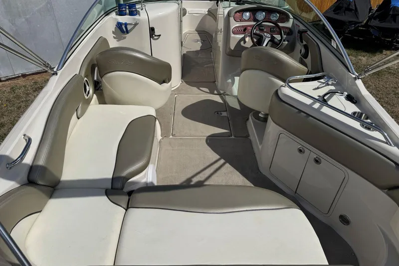 Slide: The Image of 2006 Sea Ray 240 Sundeck interior with beige seating and steering console. - 13