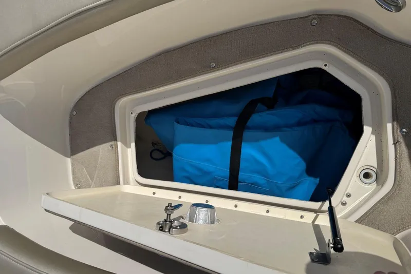 Slide: The Image of Storage compartment on a 2006 Sea Ray 240 Sundeck with blue bag inside. - 26