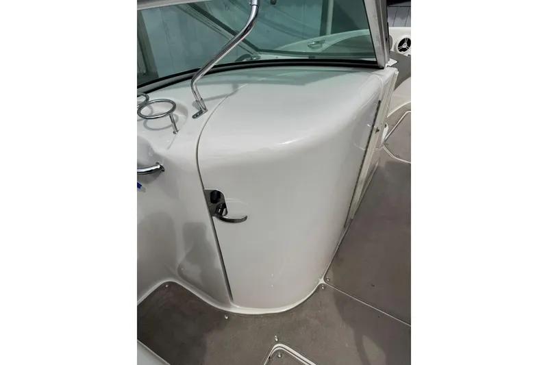Slide: The Image of 2006 Sea Ray 240 Sundeck interior with sleek white console and windshield. - 31