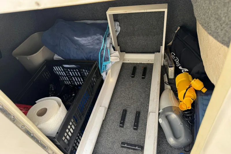 Slide: The Image of Storage compartment of a 2006 Sea Ray 240 Sundeck with various boating supplies. - 36