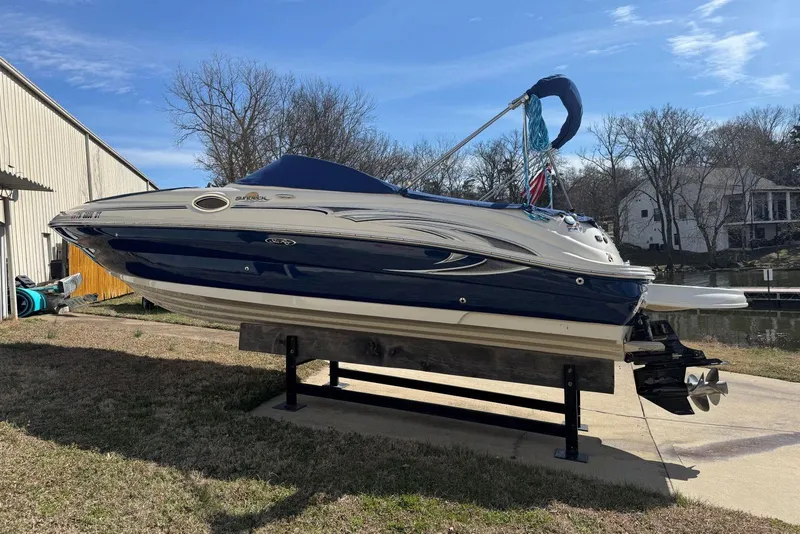 Slide: The Image of 2006 Sea Ray 240 Sundeck boat on lift, blue and white design, near waterfront. - 42