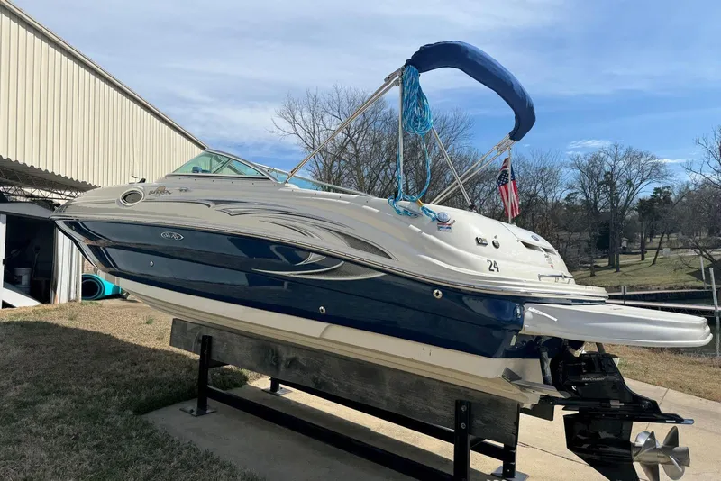 Slide: The Image of 2006 Sea Ray 240 Sundeck boat on lift, blue and white exterior, sunny day. - 6